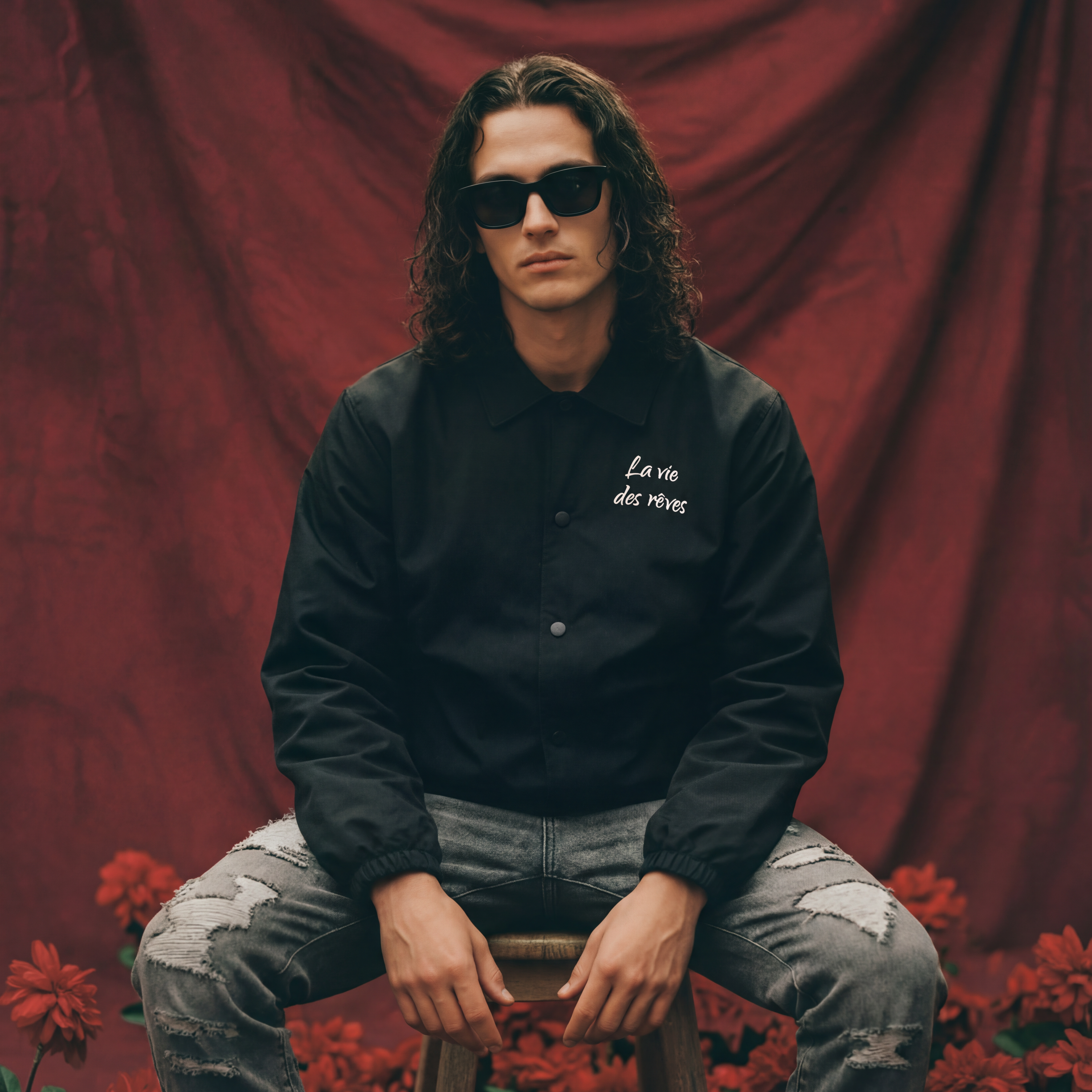 Man wearing sunglasses and a black la vie des reves jacket and grey distressed carpenter jeans.