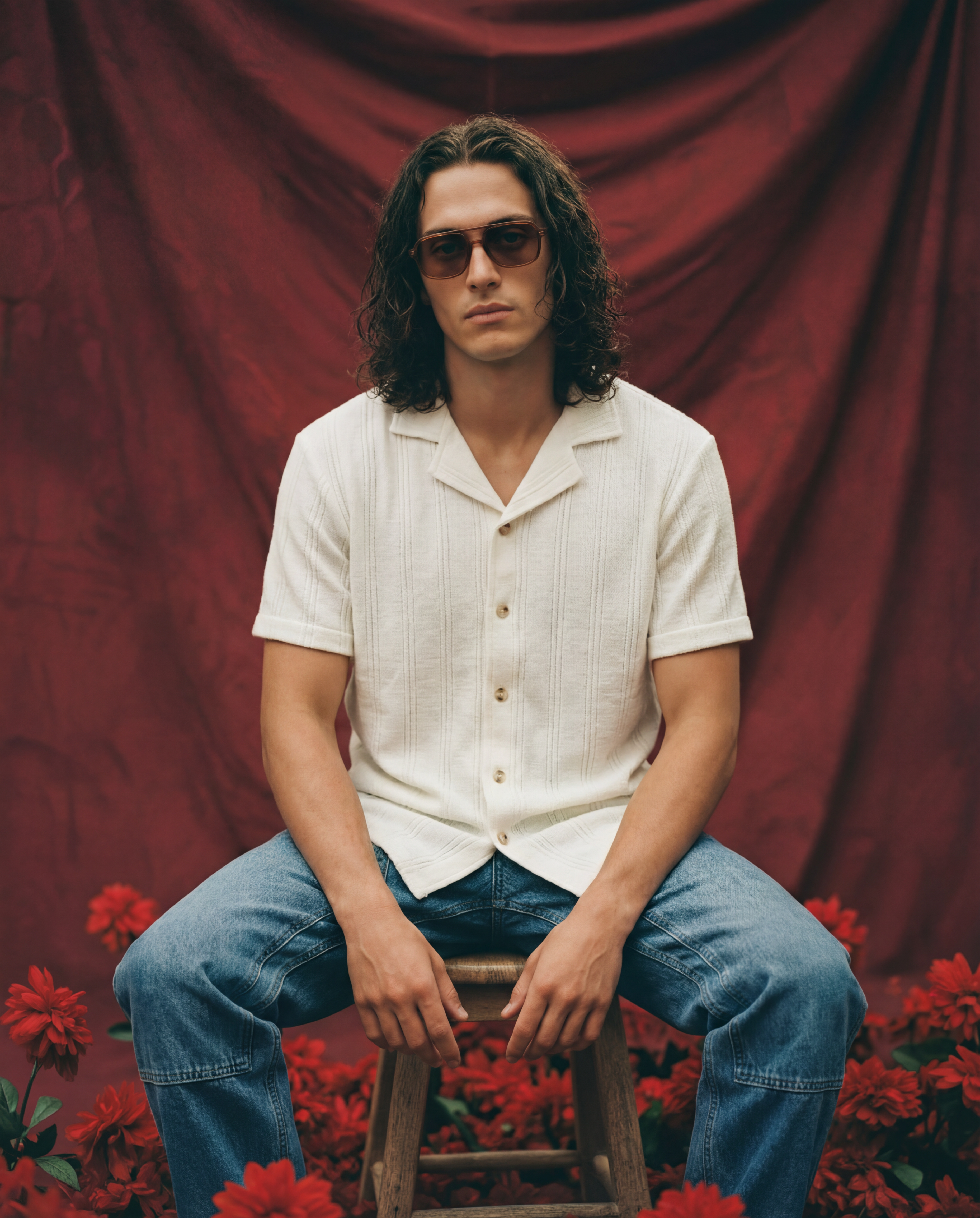 Man sitting wearing a cream knitted shirt with blue carpenter jeans