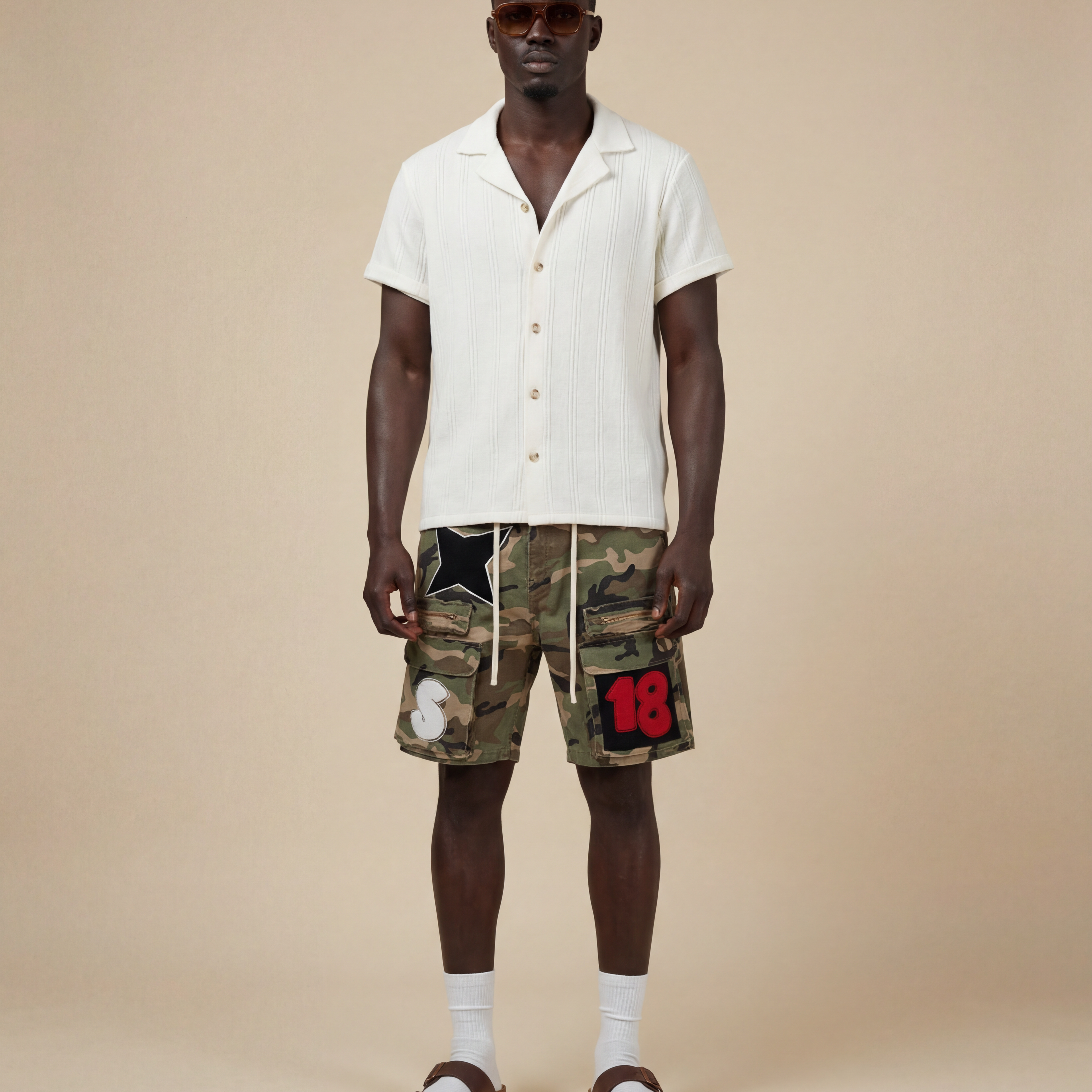 Man wearing a cream shirt and camouflage cargo shorts with patches