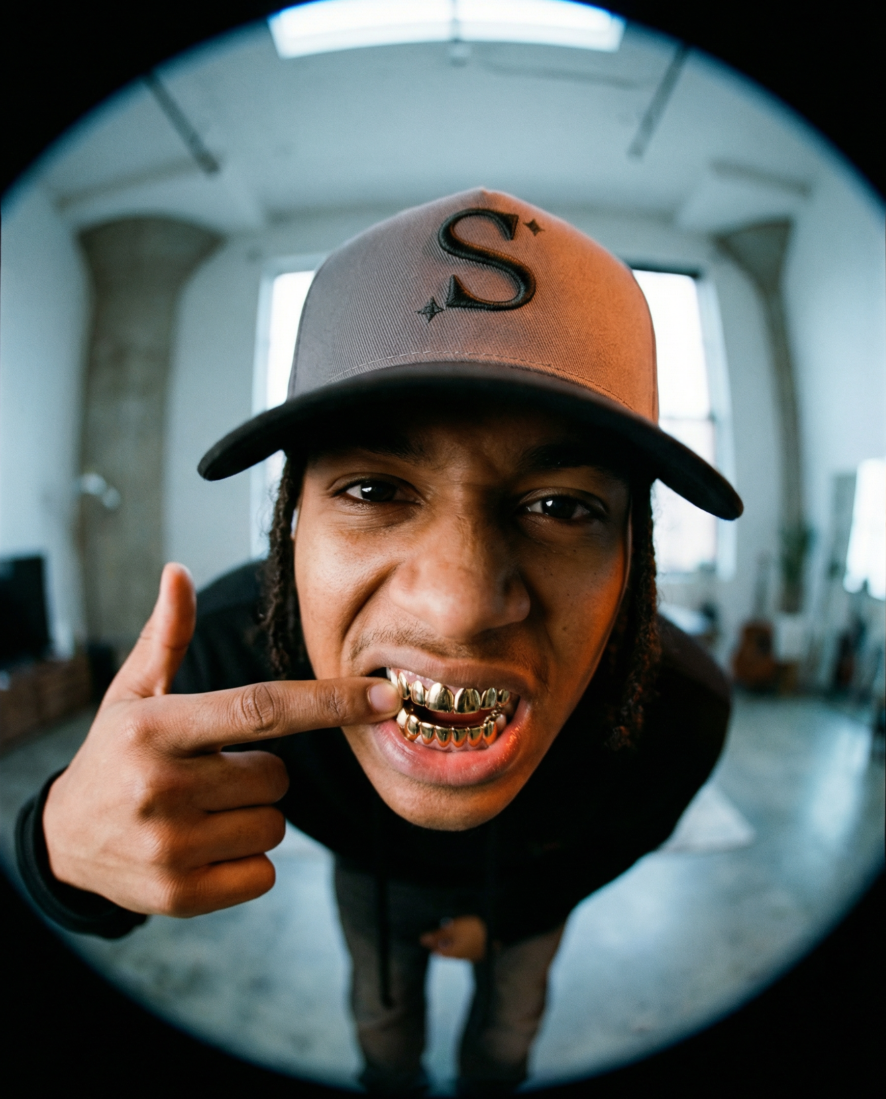 person wearing a grey trucker cap with a black 'S' logo