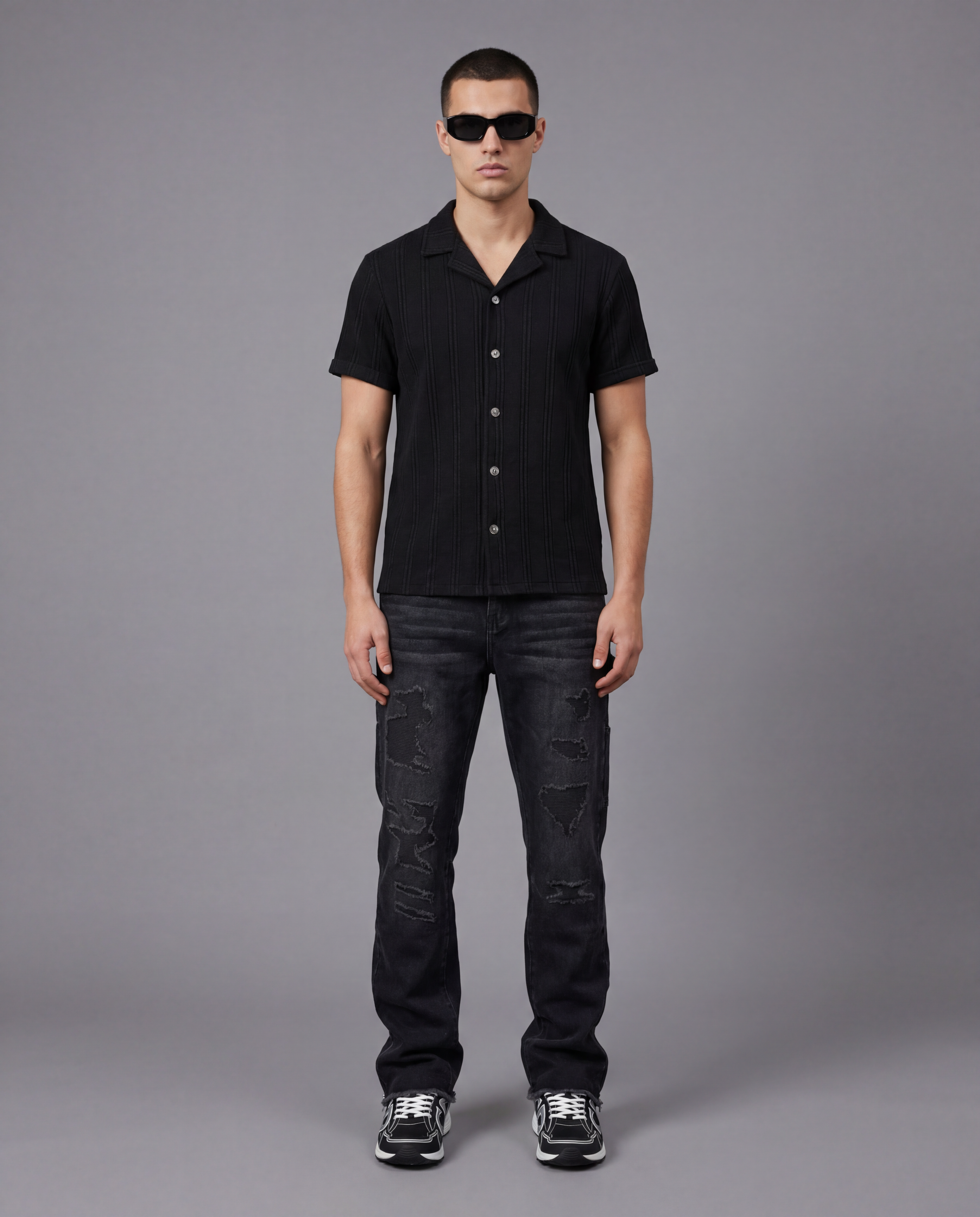 Man wearing a black shirt and black distressed carpenter jeans.