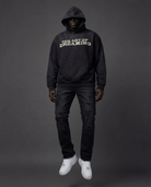 Person wearing a black hoodie with 'The Art of Dreaming' text along with black distressed carpenter.