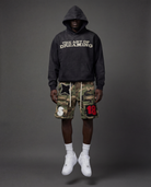 Person wearing a black hoodie with 'The Art of Dreaming' text and camouflage cargo shorts.